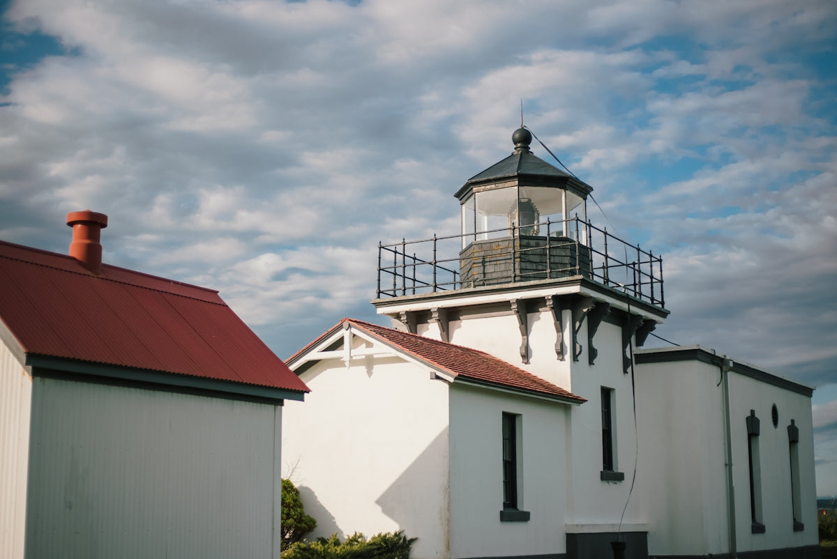 a white building with a red roof and a light house