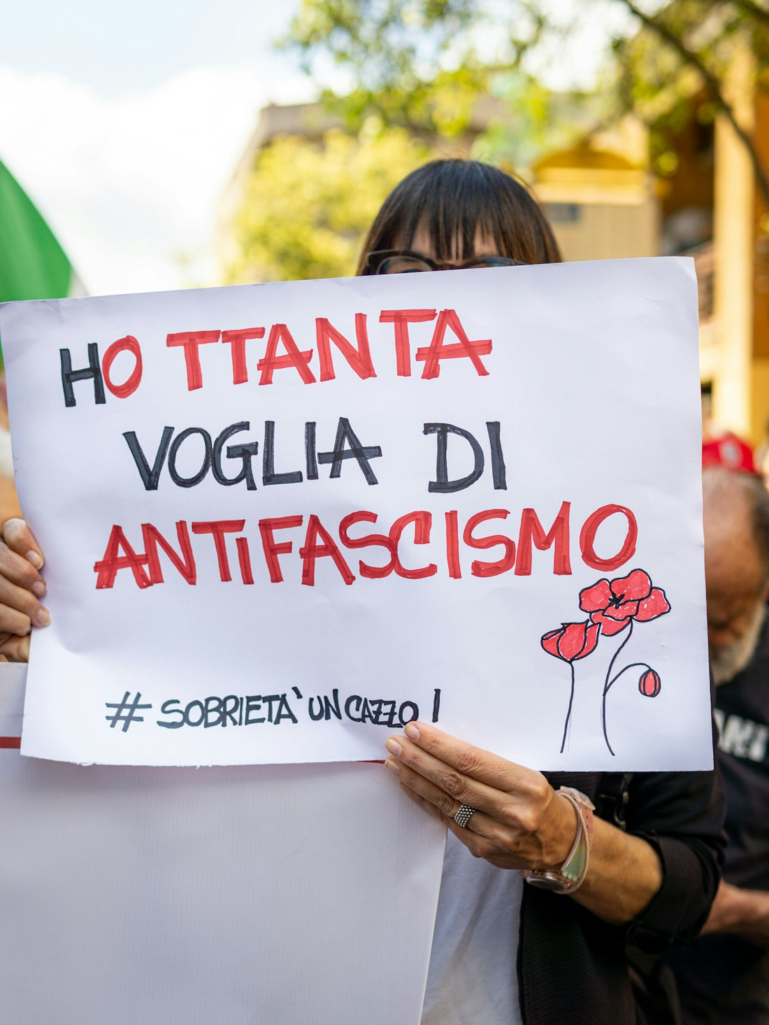 Woman holds a sign expressing anti-fascist sentiment.